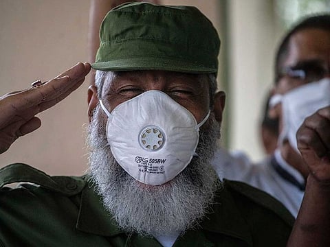 A man wearing a military uniform salutes during the playing of Cuba's national anthem on May Day, or International Workers' Day, outside a health center in Havana, Cuba, Friday, May 1, 2020. Due to the coronavirus pandemic, the Cuban government called off May Day celebrations, an event that showcases a huge rally and march in Revolution Square. 