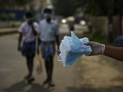 People wearing masks walk past a man selling face masks by a roadside in Kochi, Kerala May 2.