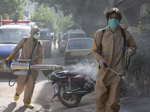 Volunteers disinfect the area which authorities sealed off after a group of people tested positive for the coronavirus on May 1, in Karachi. 