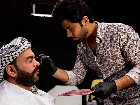 Iraqi actor Ayad al-Atabi, (L), gets his makeup done on the set of a parody sketch video of Bab al-Hara, an adaptation of an iconic long-running Syrian television drama, in Iraq's southern port city of Basra on April 22, 2020. 