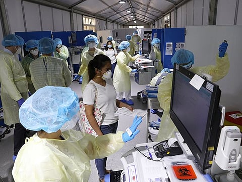File photo: A woman waits to be tested by medical staff wearing protective equipment, at a hospital in Abu Dhabi. 