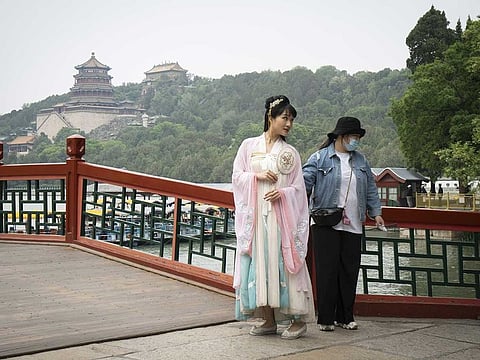 A visitor dressed in traditional hanfu clothing, left, poses for a photograph at the Summer Palace in Beijing, China, on Monday, May 4, 2020. 