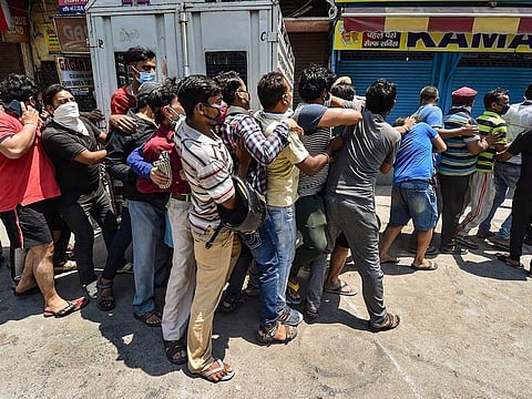 People violate social distancing norms as they stand in a queue to buy alcohol after authorities permitted opening of wine shops with certain restrictions, during the ongoing COVID-19 nationwide lockdown, at Jheel Khurenja in East Delhi, Tuesday, May 5, 2020.