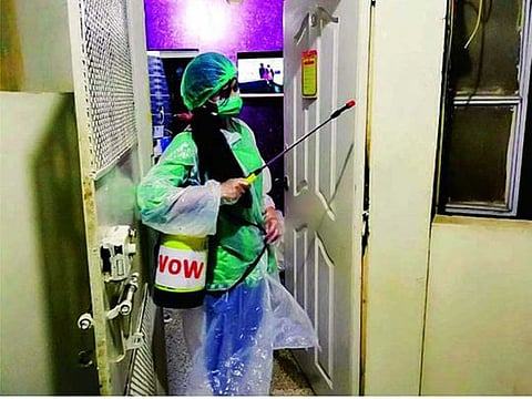 A worker of Voice of Women, a Karachi-based organisation, spraying as part of the disinfection campaign in Karachi. 