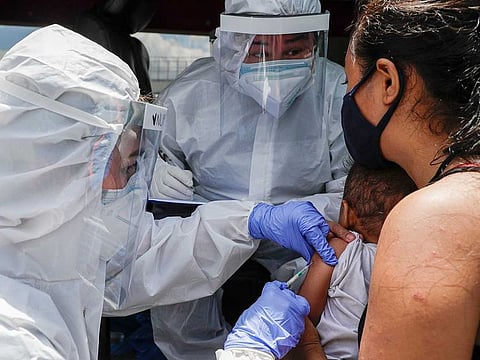Health workers wearing protective suits immunize small children against measles from their vehicle during an enhanced community quarantine to prevent the spread of the new coronavirus in Manila, Philippines.