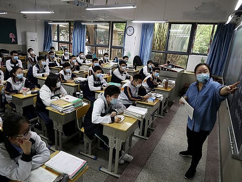A teacher and senior high school students wearing face masks are seen inside a classroom on their first day of returning to campus following the coronavirus disease (COVID-19) outbreak, in Wuhan, Hubei province, China May 6, 2020