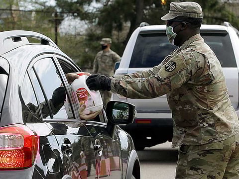 A Massachusetts US Army National Guard soldier hands a gallon container of milk to a recipient in a vehicle at an event sponsored in part by Dairy Farmers of America, at Boston College High School, Thursday, May 7, 2020, in Boston. Dairy farmers have a milk surplus because demand has dropped as schools and restaurants are closed during the corona virus pandemic, and some farmers have had to pour excess milk away.