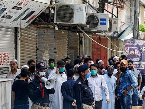 A police officer uses a megaphone to disperse shopkeepers, who gathered to reopen their shops at a closed electronics market, as the lockdown continues during the efforts to stop the spread of the coronavirus disease (COVID-19), in Karachi, Pakistan April 27, 2020. 