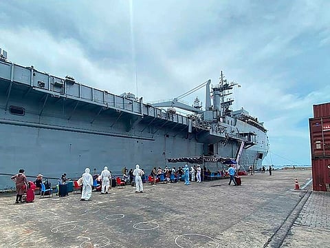 In this handout photograph taken on May 8, 2020 and released by the Maldives Ports Limited, officials wearing protective gear check Indian citizens before boarding the INS Jalashwa ship to be evacuated to India, as part of a massive repatriation effort due to the COVID-19 coronavirus pandemic, at the port of Male. 