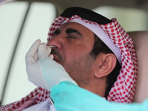 A health worker, wearing personal protective equipment, collects a swab sample from a man at a drive-thru testing service for COVID-19 coronavirus in the Qatari capital Doha, on May 7.