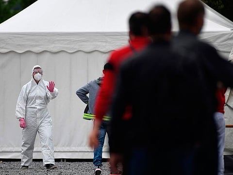 Workers queue for a coronavirus test at a testing station on the factory premises of the Westfleisch meat processing company in Hamm, western Germany, on May 10, 2020. 