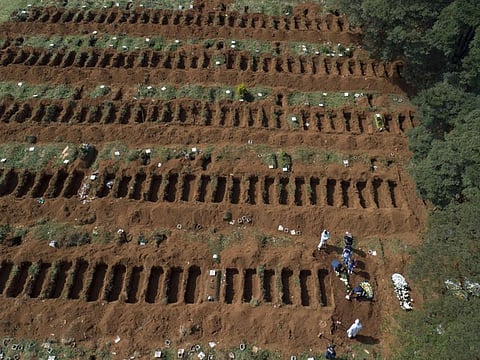 Cemetery workers wearing protective clothing stand by as family members attend a burial service at the Vila Formosa cemetery, amid the COVID-19 pandemic, in Sao Paulo.