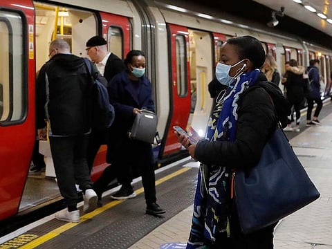 People wearing face masks to protect against the coronavirus, travel by the subway in London, Tuesday, May 12, 2020, as the country continues in lockdown. Britain's Prime Minister Boris Johnson announced Sunday that people could return to work if they could not work from home. 