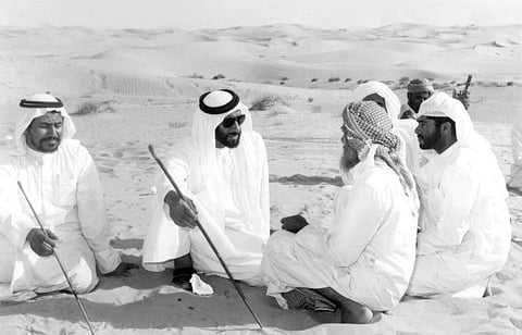 President His Highness Shaikh Zayed Bin Sultan Al Nahyan chatting with a group Emiratis (bedouin) in the desert in 1970s. 