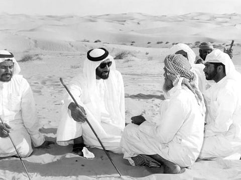 President His Highness Shaikh Zayed Bin Sultan Al Nahyan chatting with a group Emiratis (bedouin) in the desert in 1970s. 