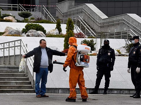Emergencies personnel wearing protective gear spray disinfectant on a man at the site of a fire at the Saint George hospital in Saint Petersburg on May 12, 2020. A fire at a hospital in Russia's second city Saint Petersburg on May 12 killed five coronavirus patients who had been attached to ventilators, officials and news agencies said.