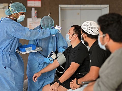 A health worker checks the body temperature of a migrant worker at a clinic in Dubai.  
