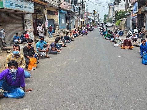 Migrant labourers from Bihar sit along a road after they were stopped by the police while they were trying to leave for their homes, amid COVID-19 lockdown in Moradabad, Tuesday, May 12, 2020. 
