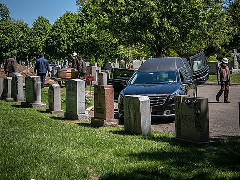 Cemetery workers prepare to bury a casket without any family present because of coronavirus restrictions at Holy Cross Cemetery in the Brooklyn borough of New York