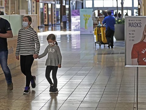 Shoppers walks past a sign encouraging masks at SouthPark Mall, Wednesday, May 13, 2020, in Strongsville, Ohio. Ohio retail businesses reopened Tuesday following a nearly two-month-long shutdown ordered by Gov. Mike DeWine to limit the spread of the coronavirus.  