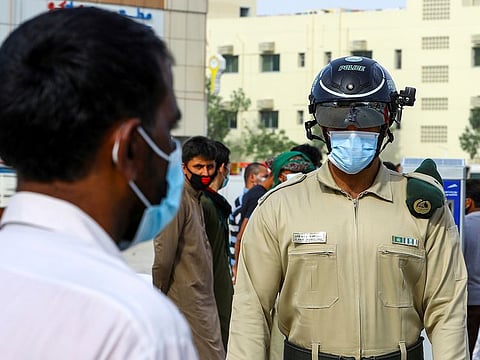 A police officer wears a smart helmet as he uses it to check the temperature of workers in Dubai. 