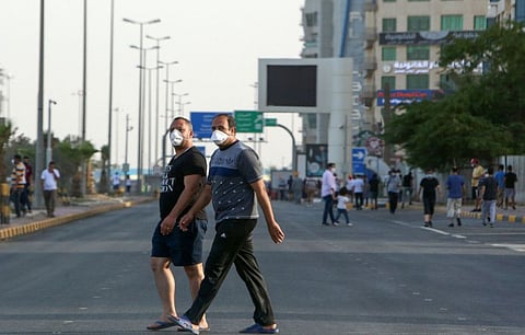 Mask-clad residents walk in a neighbourhood of Kuwait city on May 12.