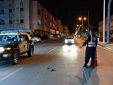 A Saudi security guard enforces compliance with a nighttime curfew. 