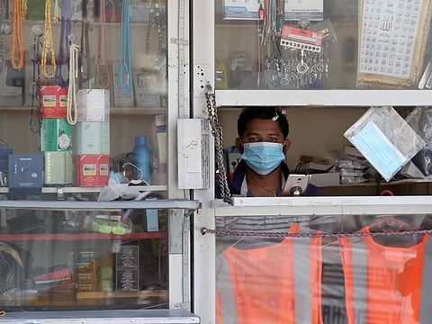 A shopkeeper wearing a protective mask looks out of a window at his store in Qatar's capital Doha, on May 17, 2020, as the country begins enforcing the world's toughest penalties for failing to wear masks in public.