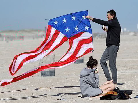 Stephen Wilmer, of Lindenhurst, N.Y., works at getting his kite aloft in the breeze as his daughter Emma adjusts her protective face mask as the family visited Jones Beach, in Wantagh, N.Y., Thursday, May 21, 2020, amid the coronavirus pandemic.