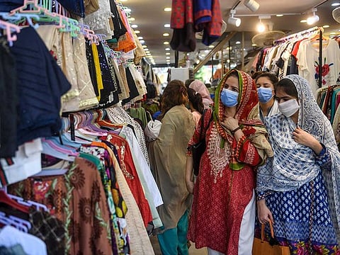 In this picture taken on May 20, 2020, people wearing facemasks shop for clothes at a market ahead of the Eid Al Fitr festival which marks the end of the Muslim holy month of Ramadan after the government eased a nationwide lockdown imposed as a preventive measure against the COVID-19 coronavirus, in Karachi. 
