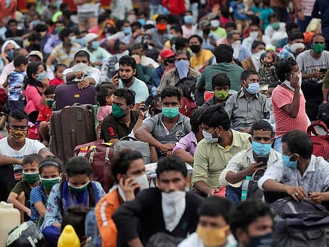 Migrant workers wait outside a railway station to catch a train to return to their homes, in Mumbai, India, Friday, May 15, 2020. 