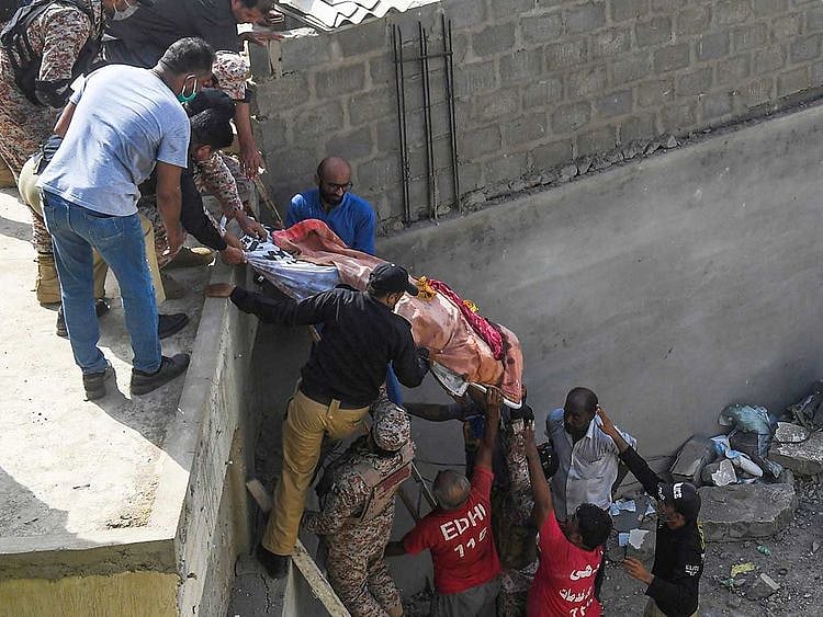 Rescue workers move a body from the site after a Pakistan International Airlines aircraft after crashed at a  residential area in Karachi on May 22, 2020. 