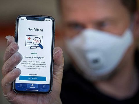 A man holds a smartphone showing a tracking and tracing app to try to halt a return of the new coronavirus