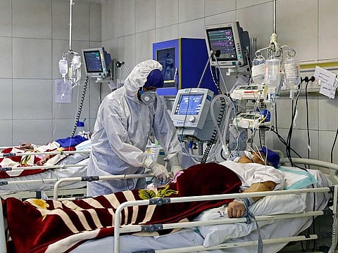 In this March 1, 2020 file photo, a medic treats a patient infected with coronavirus, at a hospital in Tehran, Iran. 