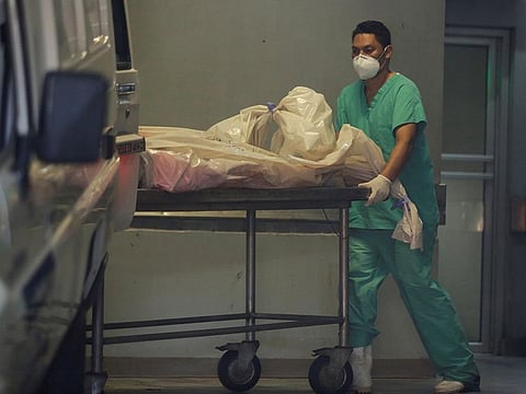 A morgue worker carries a bag containing one body after six inmates died and two more were injured in the National Women's Penitentiary for Social Adaptation, at a morgue in Tegucigalpa, Honduras May 24, 2020.