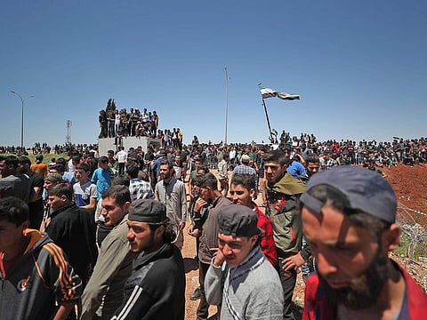 Syrian protesters, displaced from their homes in the rebel bastion of Idlib which had been under assault by government forces earlier this year, gather outside a Turkish army base near Syria's northwestern city of Idlib on May 25, 2020.