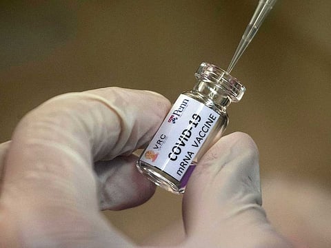 A lab technician extracts a portion of a COVID-19 vaccine candidate during testing.