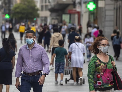 People wearing face masks to protect against coronavirus, walk in downtown Madrid, Spain, Tuesday, May 26, 2020, as the lockdown continues. 