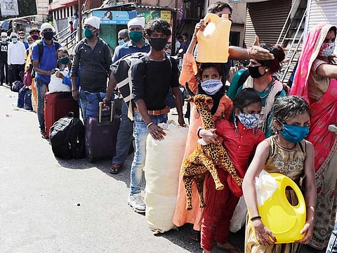 Migrant workers and their families gather for transport to the railway station for their onward journey to their home states, at Dharavi in Mumbai, India, Tuesday, May 26, 2020. 