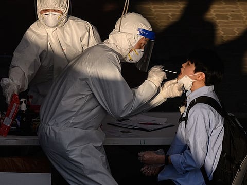 A health worker administers a swab at a temporary COVID-19 novel coronavirus testing centre in Bucheon, south of Seoul, on May 27, 2020.