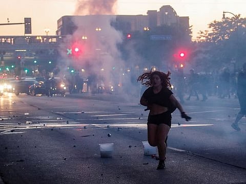 A woman reacts on a street as tear gas is used by riot police to disperse protesters as demonstrations continue after a white police officer was caught on a bystander's video pressing his knee into the neck of African-American man George Floyd, who later died at a hospital, in Minneapolis, Minnesota, U.S., May 28, 2020.