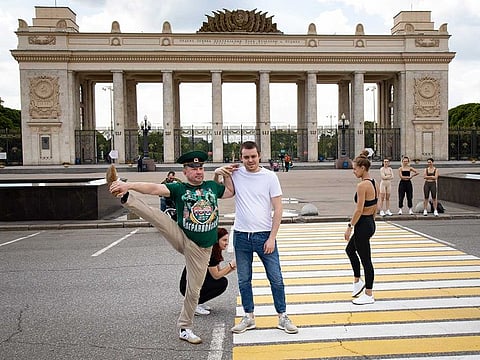 A Russian Border Guard veteran performs a stretch in front of people exercising, during the 102nd anniversary of Russia Border Guards, at Gorky Park, closed due to coronavirus pandemic, in Moscow, Russia, Thursday, May 28, 2020. 