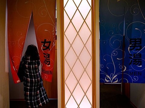 photo of Onsen, a woman enters the women's section of a Japanese hot spring or onsen in Yokohama, Kanagawa prefecture