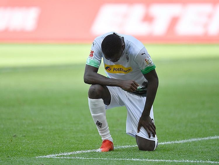 Borussia Moenchengladbach's Marcus Thuram takes a knee for George Floyd. 
