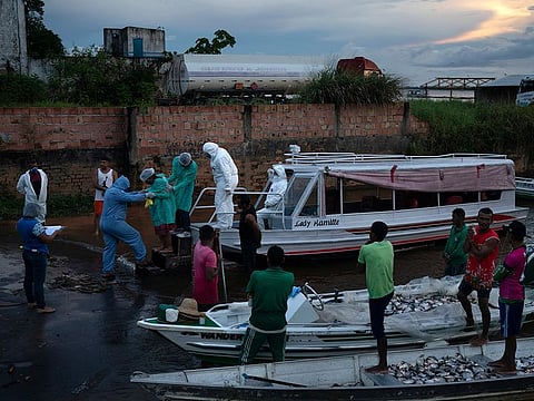 Health workers help COVID-19 patient Maria Cardoso, 73, step out of a boat to transfer her to a hospital after arriving in the port of Manacapuru, Amazonas state, Brazil, Tuesday, June 2, 2020. 