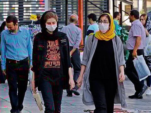 Iranians, some wearing face masks, walk along a street in the capital Tehran on June 3, 2020, amid the novel coronavirus pandemic crisis.  