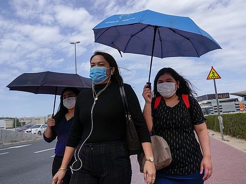 People, wearing masks as a precautionary measure, walk past a street at Business Bay area in Dubai.  