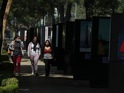 Pedestrians, one wearing a face mask, walk along an almost empty Paseo de la Reforma street in Mexico City, Tuesday, June 2, 2020.