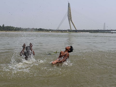 Children enjoy swimming during the afternoon on the banks of the Yamuna river, in New Delhi on Wednesday. 