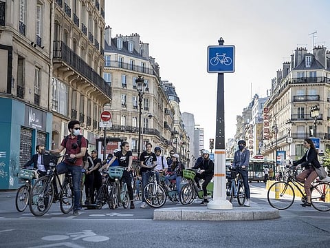 Cyclists wait to cross a road junction on Rue de Rivoli in Paris, France.